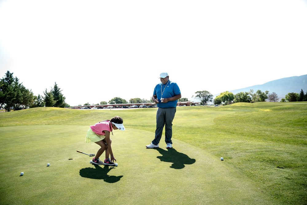 Profesor dando una clase de golf en el green